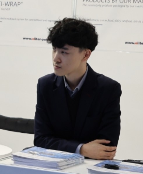Zhiwei Bao 鲍智威 headshot, owner of eliter packaging machinery and business executive, he participated in a trade fair, CONXEMAR 2024 to be more exact in the photo where he stands in the booth.